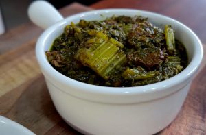 Close-up of Persian Khoresh Karafs, a celery stew with fresh herbs and tender pieces of meat served in a white bowl