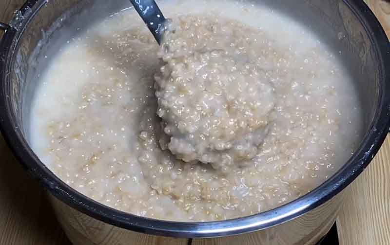 Beating the cooked wheat and meat mixture in a pot to achieve a stretchy Haleem consistency
