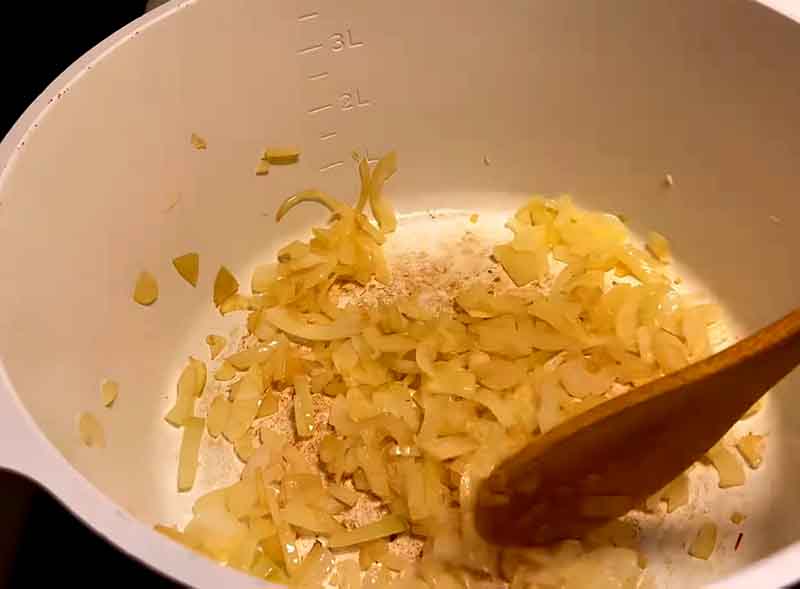 Sautéing chopped onions in a pan until golden for authentic Zanjan Jaghoor Baghoor